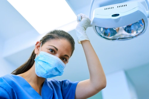 Female dental assistant holding and maneuvering overhead lamp